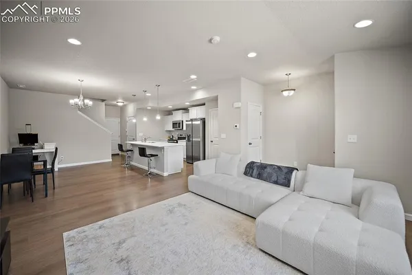 a living room with furniture and a dining table with wooden floor