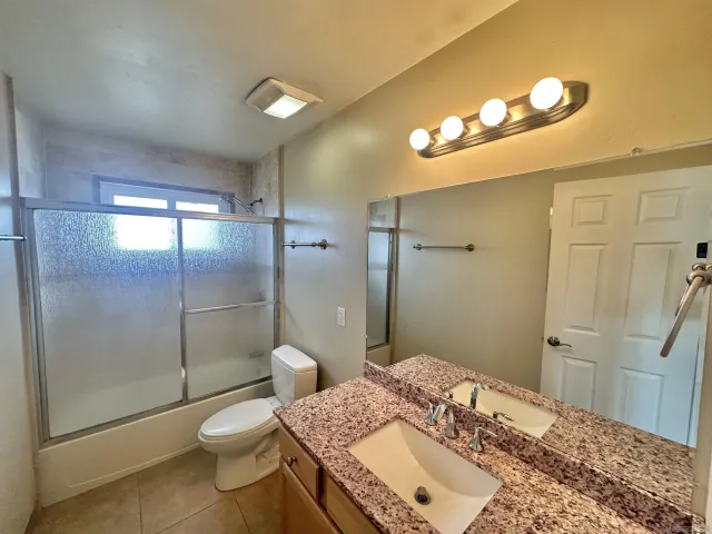 a bathroom with a granite countertop sink a toilet and shower