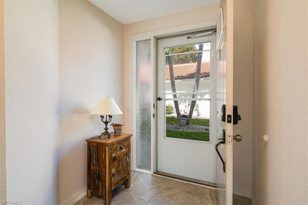 186 Gabriel Circle, Unit 3903 Naples, FL 34104 - Photo 8 of 42 Doorway featuring baseboards and a textured wall