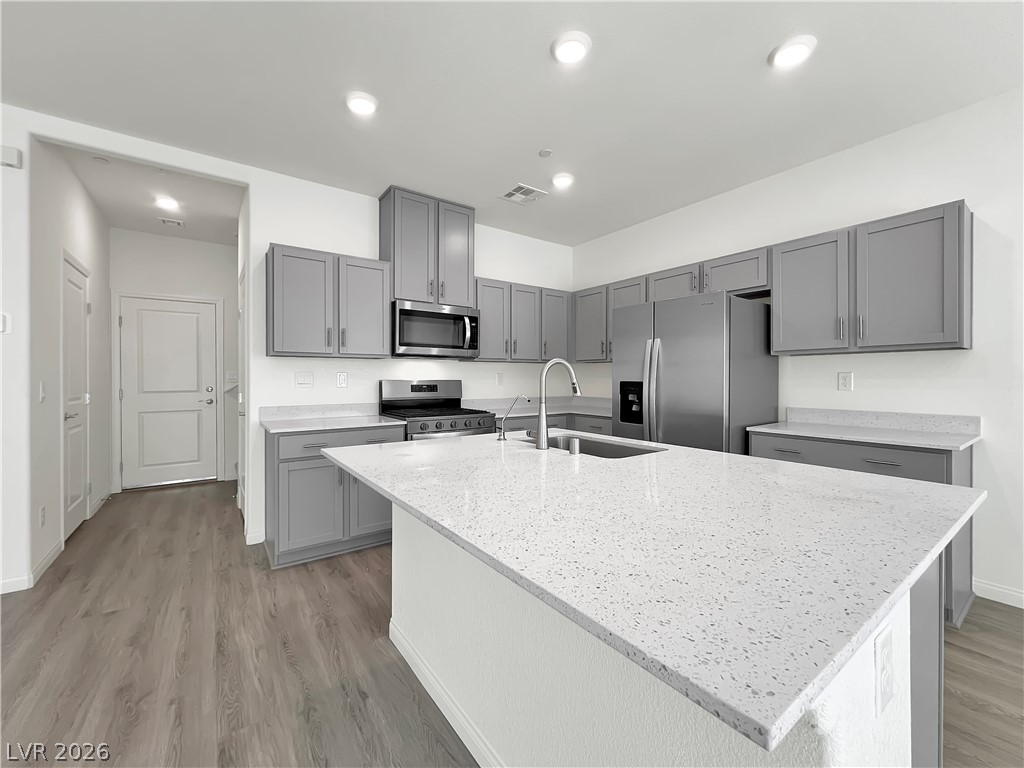 9984 Indigo Cliffs Street Las Vegas, NV 89141 - Photo 6 of 31 Kitchen featuring light stone counters, visible vents, gray cabinetry, a sink, and appliances with stainless steel finishes