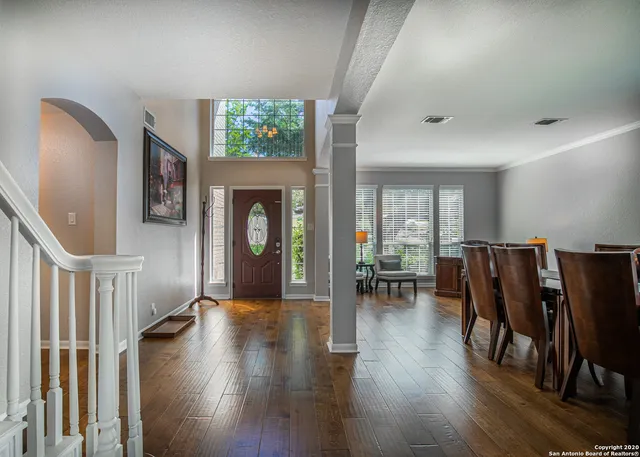 a dining room with wooden floor a chandelier a glass table and chairs