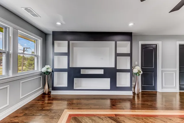 a view of an empty room with wooden floor and a window
