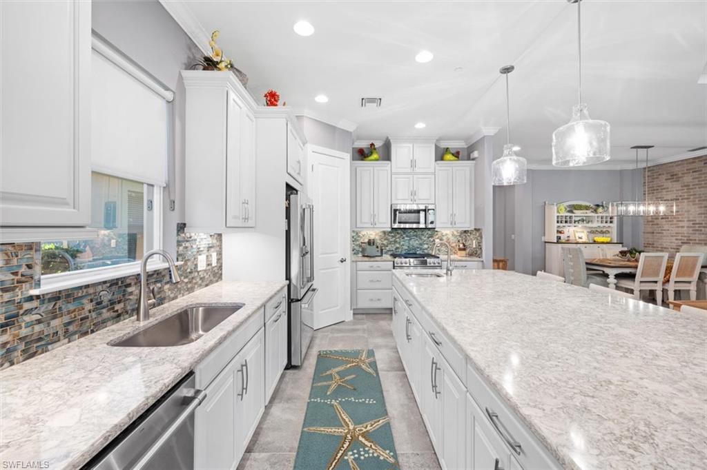 10256 Coconut Road Estero, FL 34135 - Photo 8 of 45 a large kitchen with stainless steel appliances kitchen island granite countertop a sink and cabinets