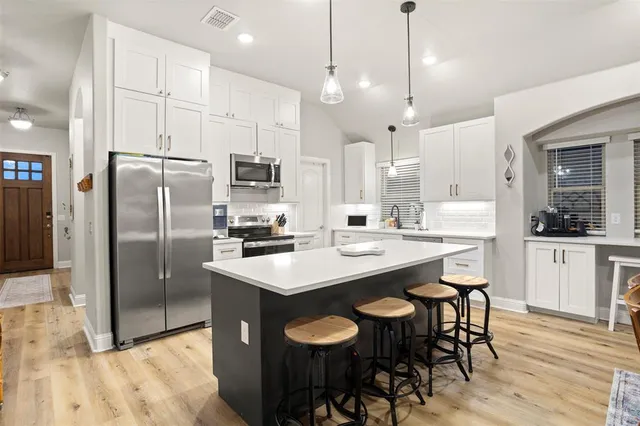 a view of a kitchen with kitchen island a sink a stove a center island a dining table and chairs