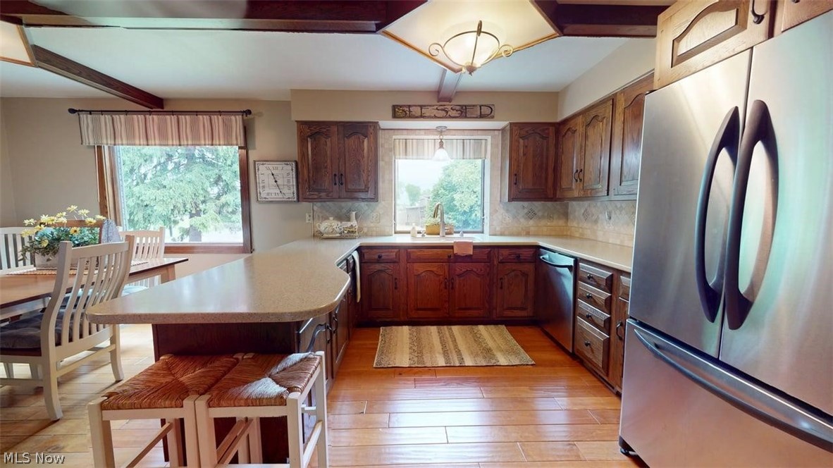 3985 Wiers Road Willard, OH 44890 - Photo 16 of 50 Well-appointed kitchen featuring wood-finish flooring, dark wood cabinetry, light-toned countertops, and a stainless steel refrigerator