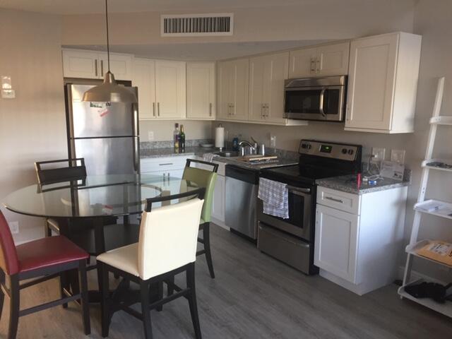 9 Deer Creek Road, Unit A206 Deerfield Beach, FL 33442 - Photo 2 of 6 a kitchen with a refrigerator a stove top oven a sink dishwasher and white cabinets with wooden floor