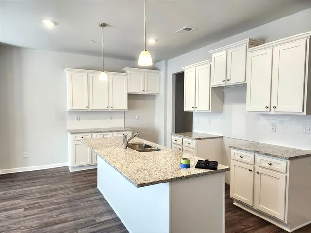 a kitchen with stainless steel appliances granite countertop a sink stove and white cabinets with wooden floor