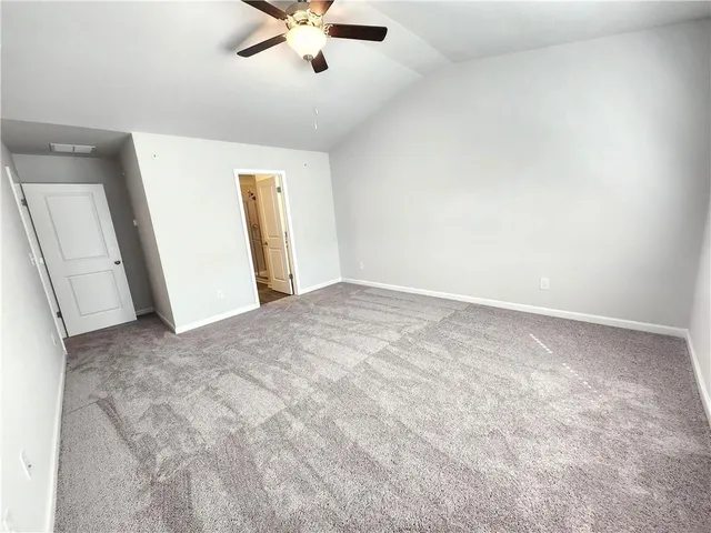 an empty room with chandelier fan and windows
