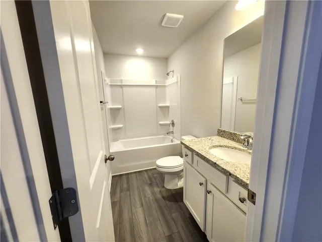 a bathroom with a granite countertop toilet a sink and a mirror