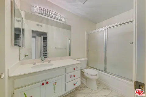 a spacious bathroom with a double vanity sink toilet mirror and shower