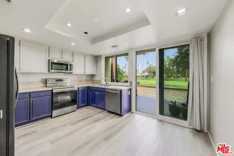 a kitchen with stainless steel appliances granite countertop a refrigerator a stove top oven a sink and dishwasher with wooden floor