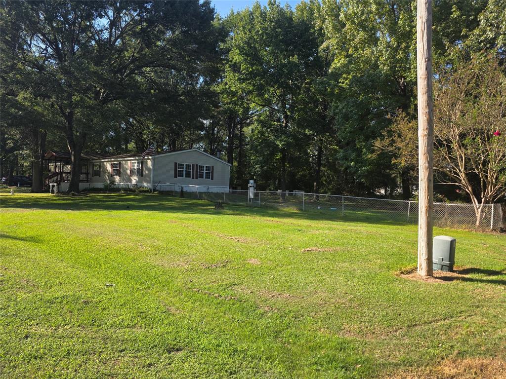 a view of a swimming pool with lawn chairs and large trees