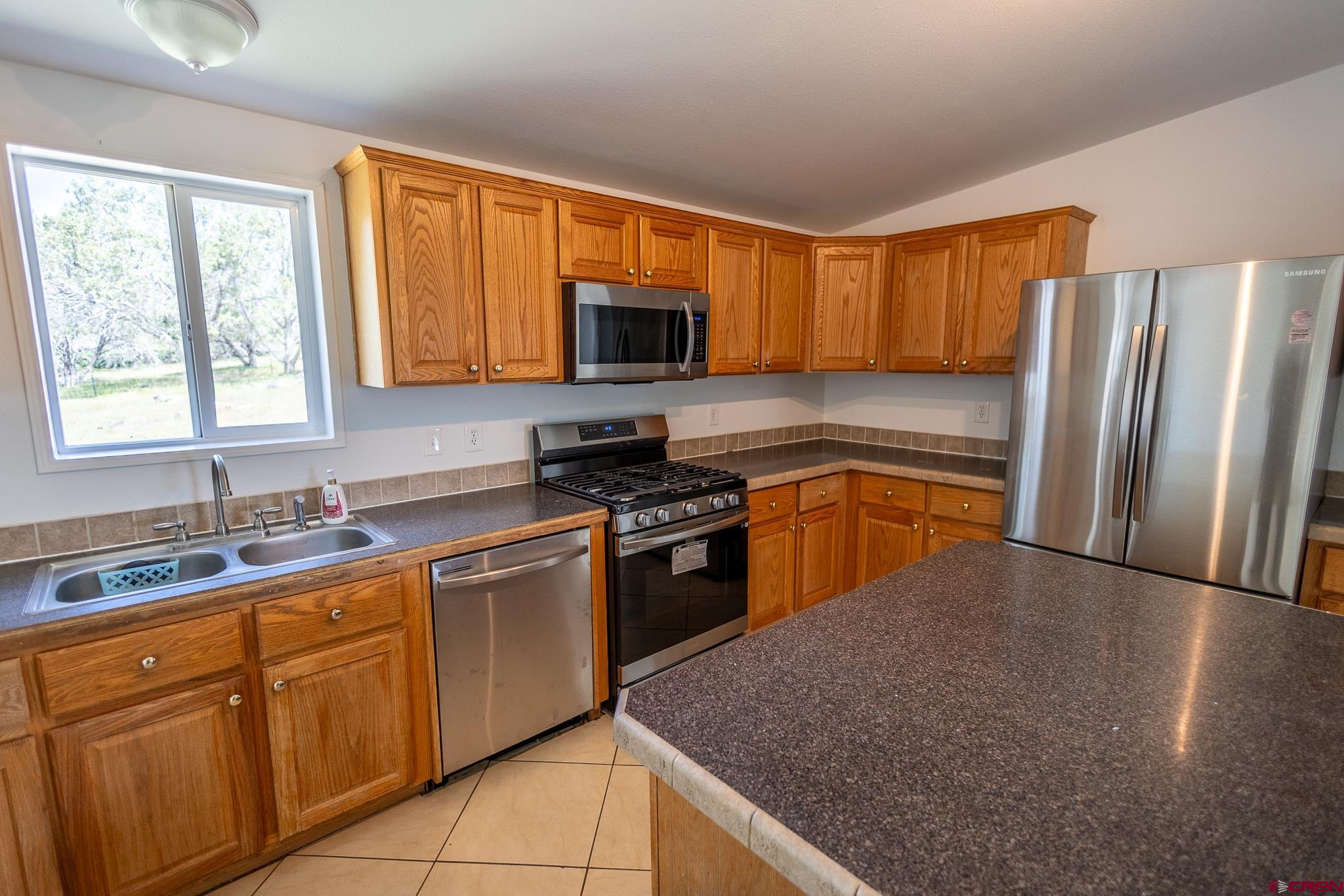 13569 3100th Road Hotchkiss, CO 81419 - Photo 11 of 29 a kitchen with stainless steel appliances granite countertop a stove a sink dishwasher a refrigerator and a microwave oven