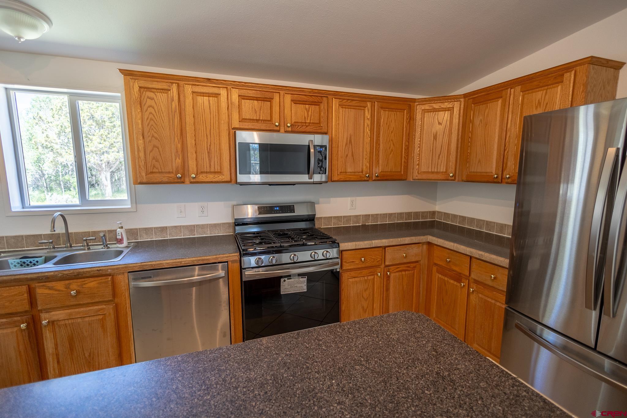 13569 3100th Road Hotchkiss, CO 81419 - Photo 12 of 29 a kitchen with stainless steel appliances granite countertop a stove a sink dishwasher a refrigerator and a microwave oven