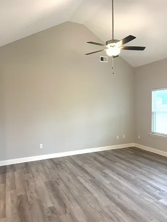 an empty room with a fan & a ceiling fan