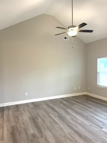 an empty room with a fan & a ceiling fan
