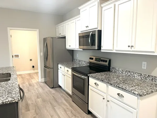 a kitchen with granite countertop white cabinets and stainless steel appliances