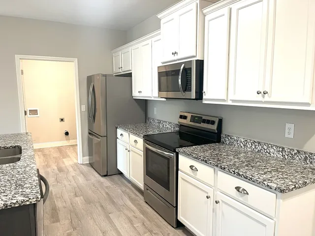 a kitchen with granite countertop white cabinets and stainless steel appliances