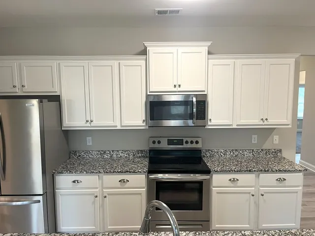 a kitchen with white cabinets and stainless steel appliances
