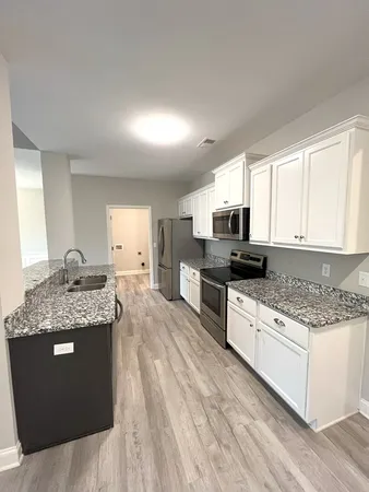 a kitchen with granite countertop a stove top oven and cabinets