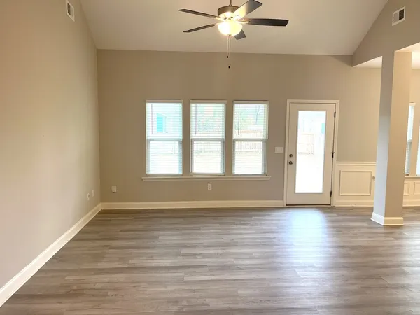 a view of an empty room with wooden floor and a window