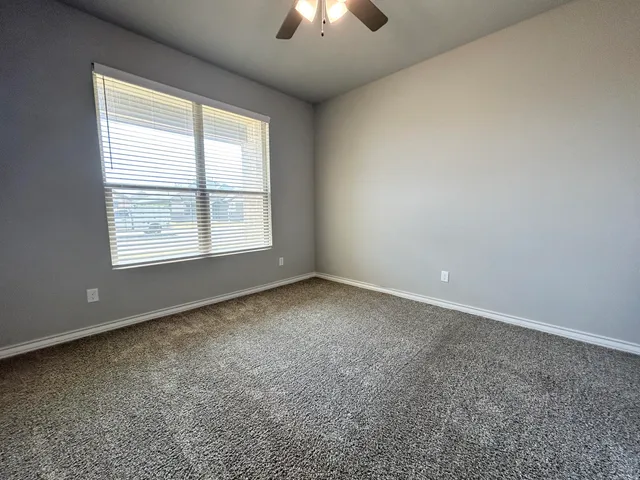 an empty room with chandelier fan and windows