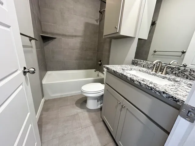 a bathroom with a granite countertop toilet a sink and a bathtub