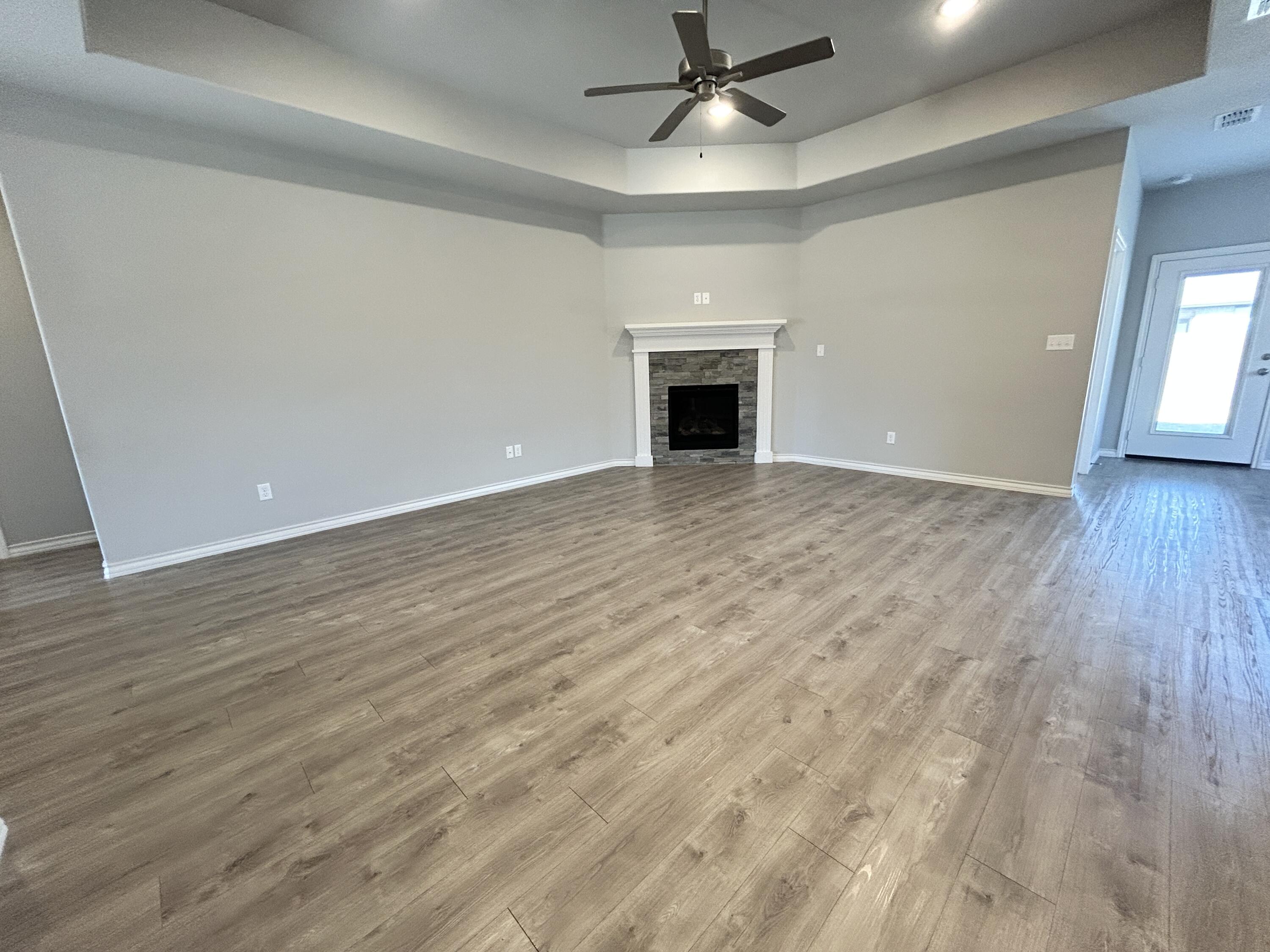 7612 61st Street Lubbock, TX 79407 - Photo 2 of 15 wooden floor in an empty room with a fireplace