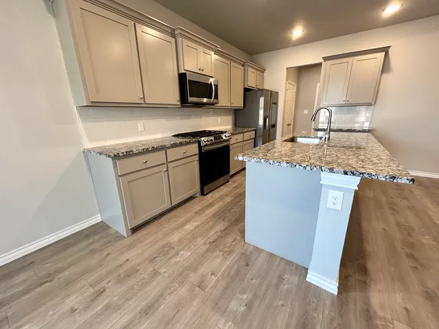 a kitchen with stainless steel appliances granite countertop a stove a sink and a microwave