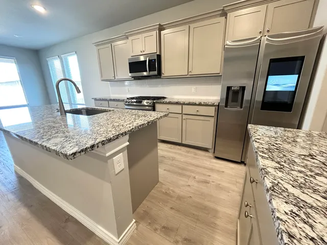 a kitchen with stainless steel appliances granite countertop a sink stove microwave and refrigerator
