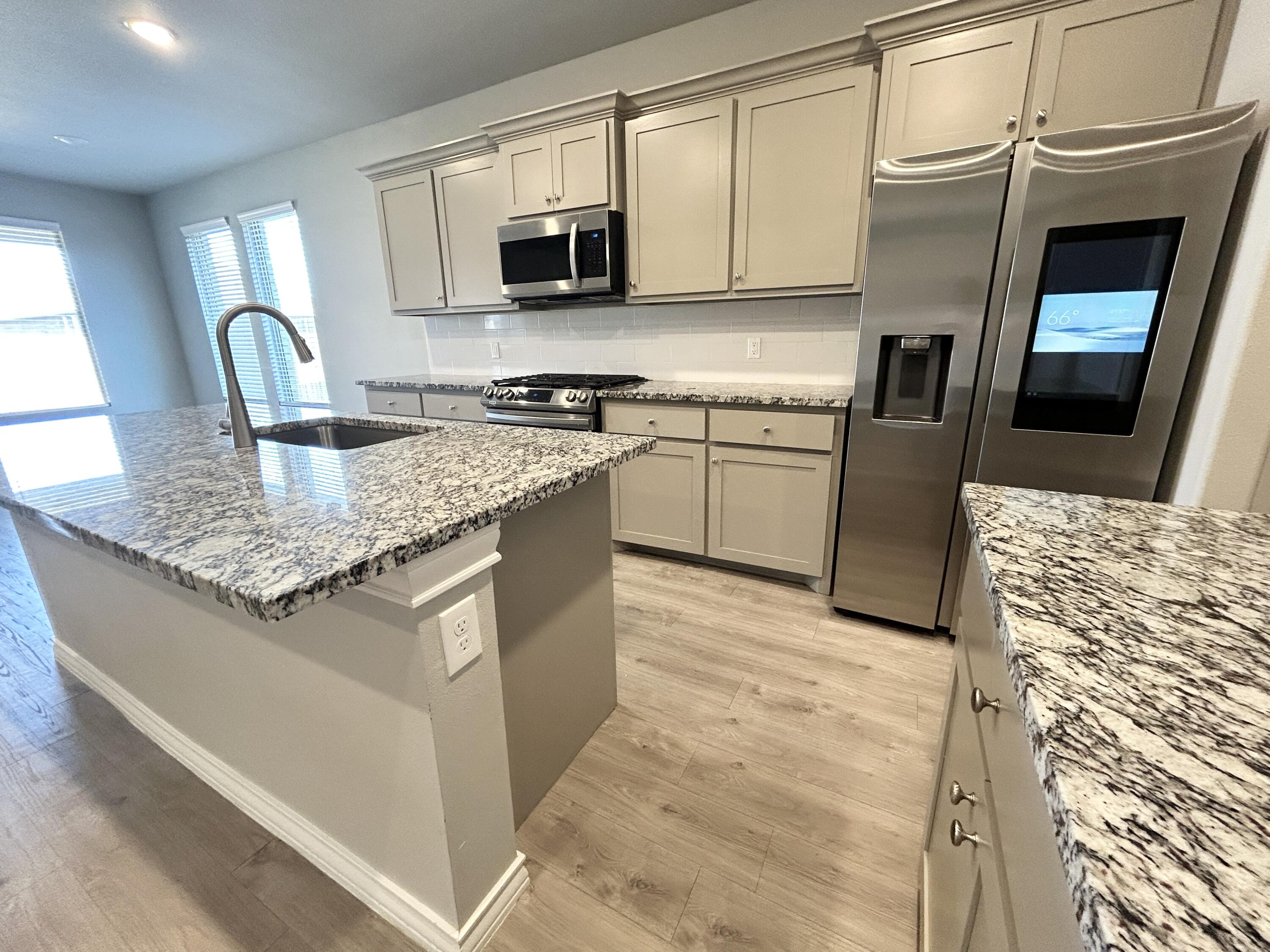 7612 61st Street Lubbock, TX 79407 - Photo 5 of 15 a kitchen with stainless steel appliances granite countertop a sink stove microwave and refrigerator