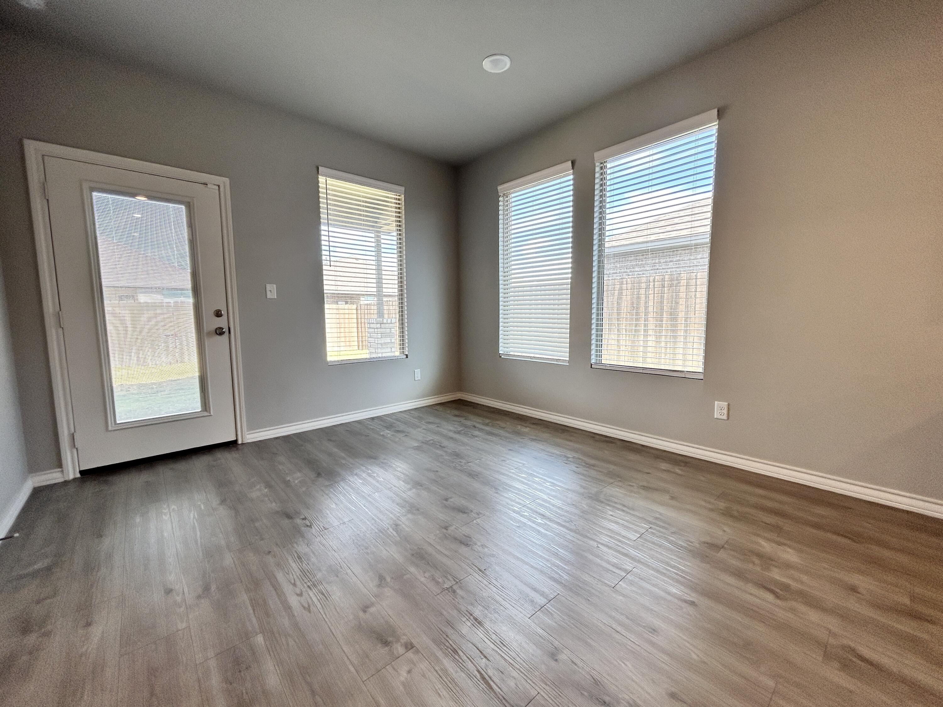 7612 61st Street Lubbock, TX 79407 - Photo 6 of 15 an empty room with wooden floor and windows