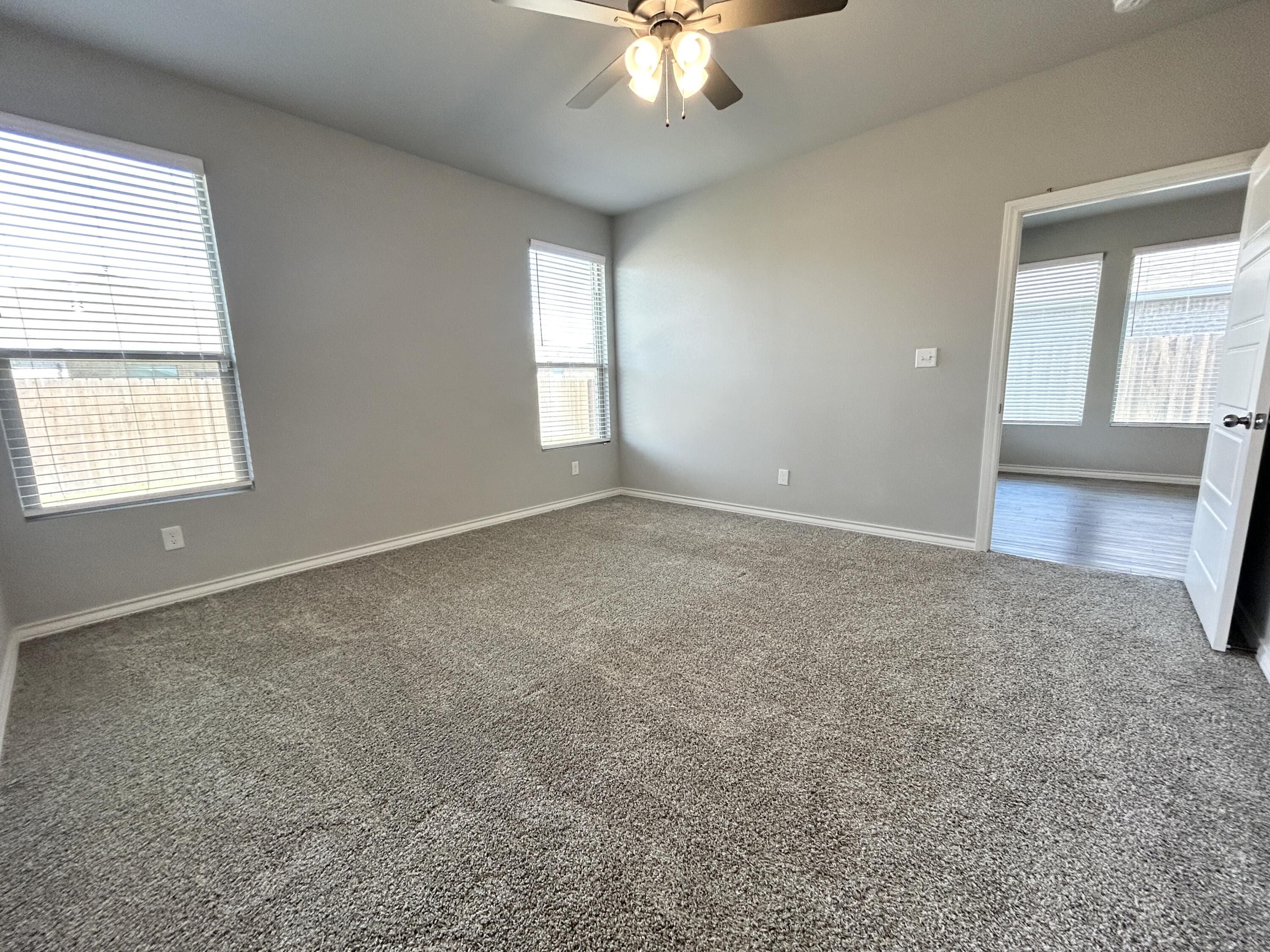 7612 61st Street Lubbock, TX 79407 - Photo 8 of 15 an empty room with windows and chandelier fan