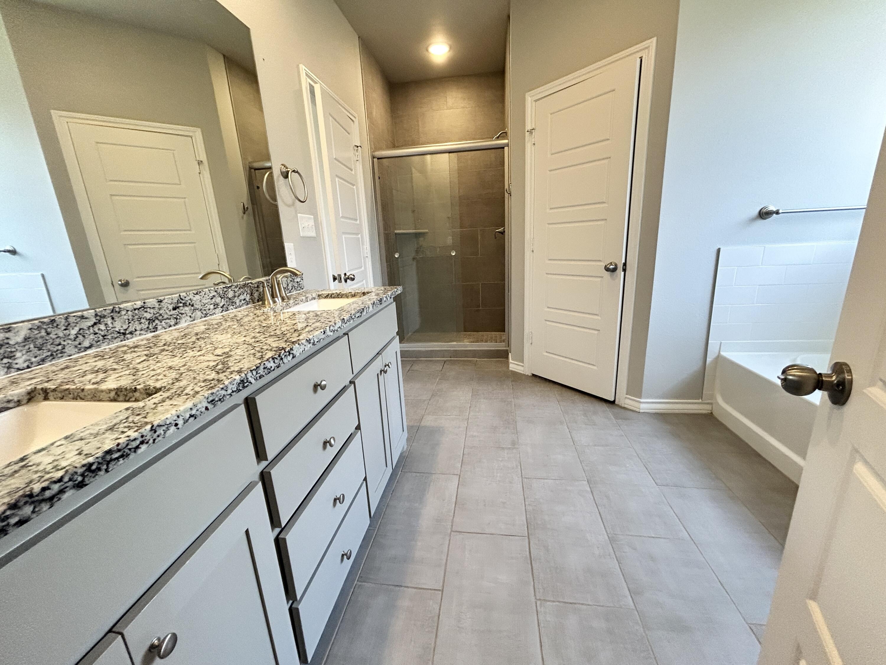 7612 61st Street Lubbock, TX 79407 - Photo 9 of 15 a bathroom with a granite countertop sink a mirror and a shower