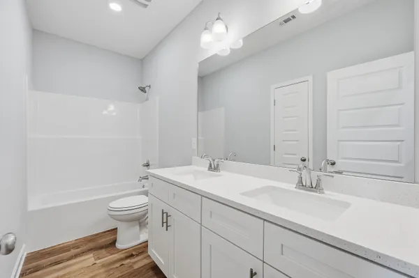 a bathroom with a double vanity sink a toilet and a tub