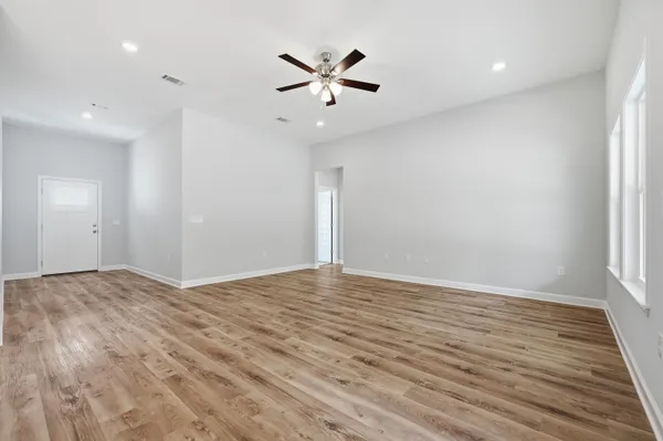 a view of empty room with wooden floor and ceiling fan
