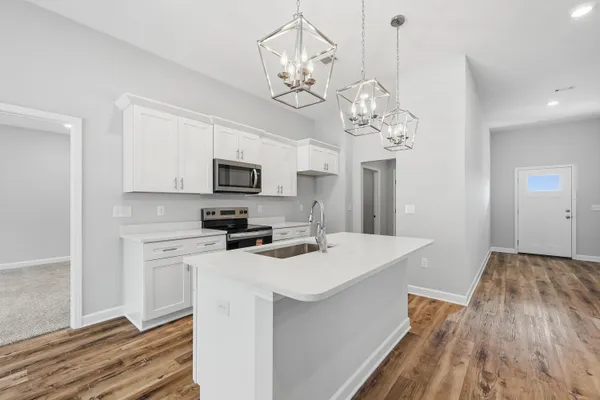 a kitchen that has a lot of white cabinets and stainless steel appliances