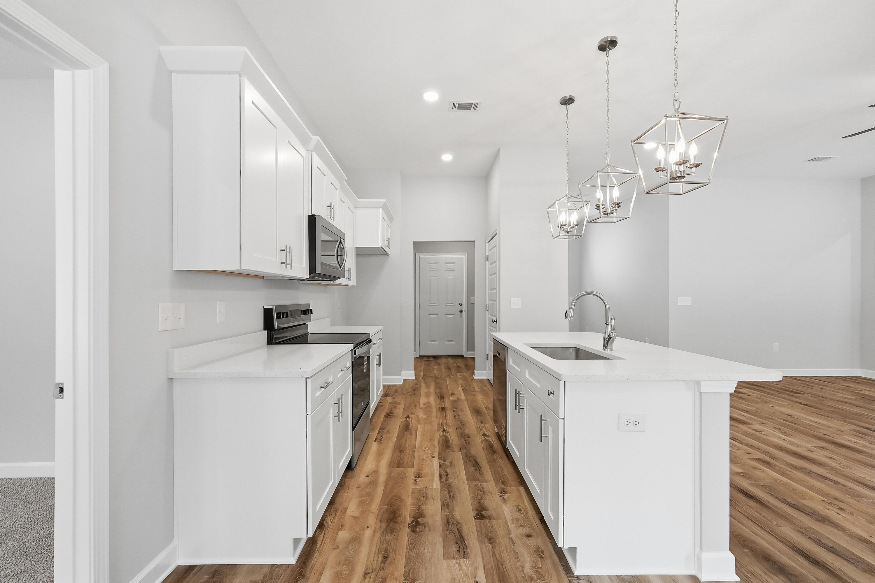 6104 Mildred's Way Crestview, FL 32539 - Photo 9 of 23 a spacious kitchen with stainless steel appliances granite countertop a sink dishwasher a stove and white cabinets with wooden floor