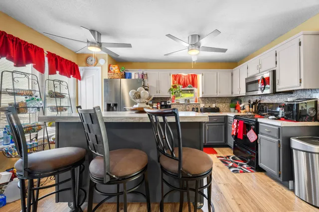 a kitchen with stainless steel appliances kitchen island granite countertop a dining table chairs and a sink