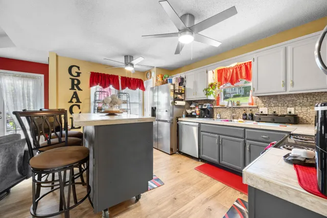 a kitchen with stainless steel appliances granite countertop a stove top oven a sink a dining table and chairs with wooden floor