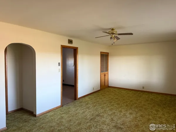 an empty room with a ceiling fan and carpet