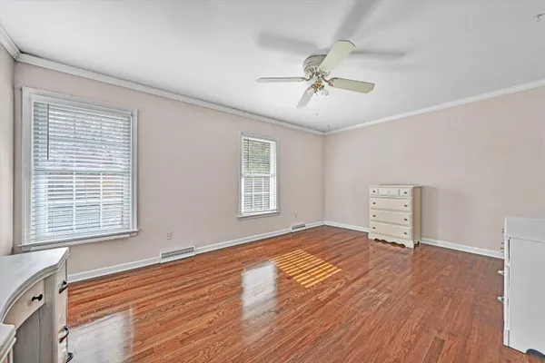 a view of empty room with wooden floor and fan