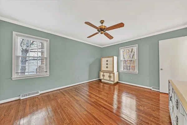 a view of an empty room with window and wooden floor