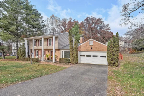 a view of a house with a yard and large trees