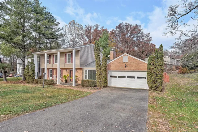 a view of a house with a yard and large trees