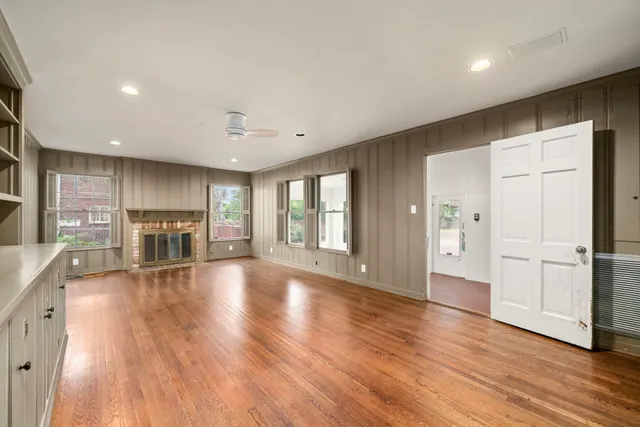 a view of an empty room with wooden floor and a kitchen