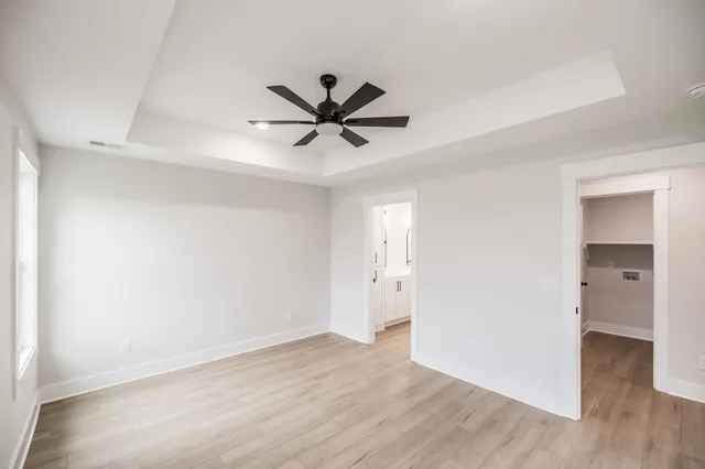 an empty room with wooden floor and a ceiling fan