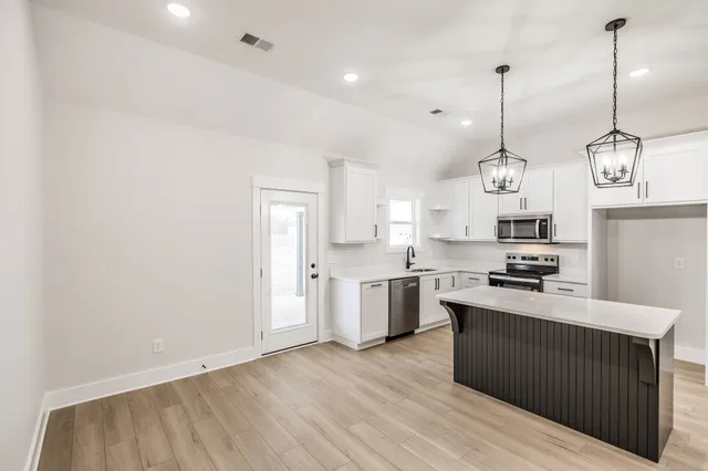 a kitchen with stainless steel appliances granite countertop a sink a stove a refrigerator and a wooden floor