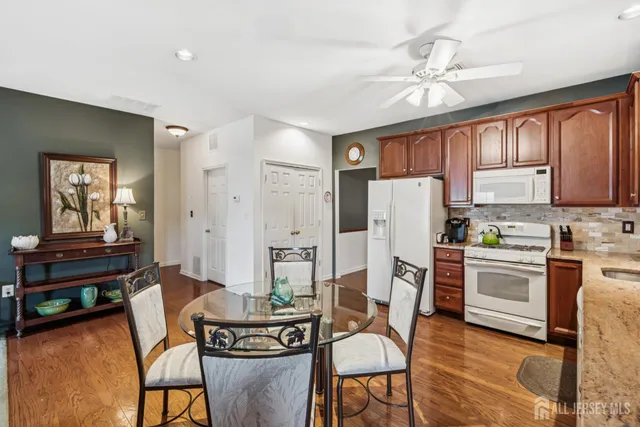 a kitchen with refrigerator a stove a dining table and chairs with wooden floor