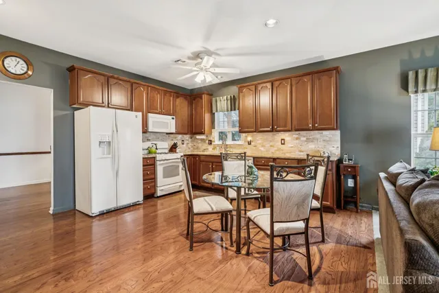 a kitchen with stainless steel appliances a dining table chairs refrigerator and sink